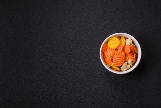 Delicious fresh vegetables steamed carrots, broccoli, cauliflower on a black plate on a dark concrete background