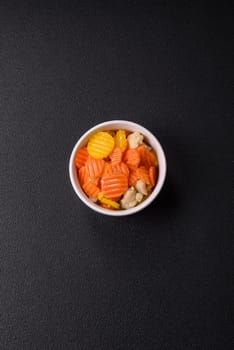 Delicious fresh vegetables steamed carrots, broccoli, cauliflower on a black plate on a dark concrete background
