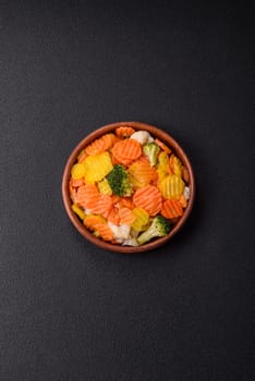 Delicious fresh vegetables steamed carrots, broccoli, cauliflower on a black plate on a dark concrete background