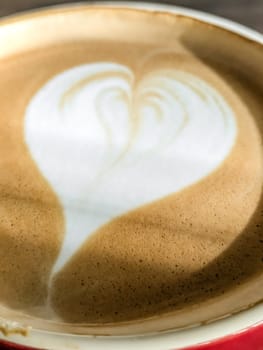 Hot cappuccino coffee with a heart pattern on the foam in a ceramic cup