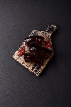 Delicious black blood sausage or black pudding with spices and herbs grilled on a black concrete background