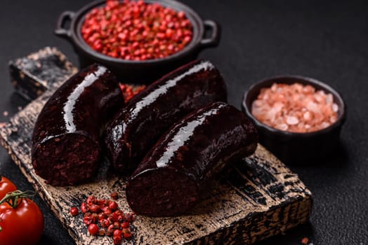 Delicious black blood sausage or black pudding with spices and herbs grilled on a black concrete background
