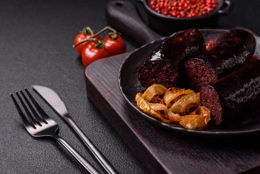 Delicious black blood sausage or black pudding with spices and herbs grilled on a black concrete background