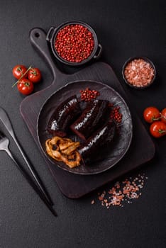 Delicious black blood sausage or black pudding with spices and herbs grilled on a black concrete background