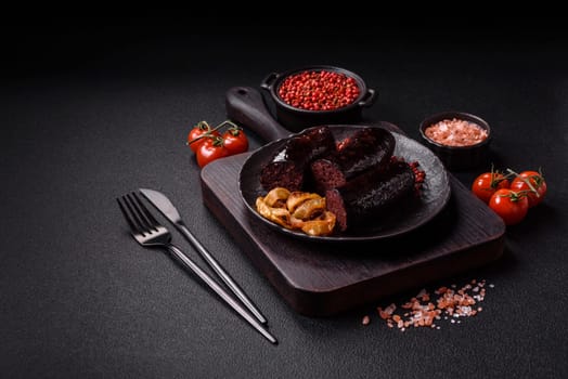 Delicious black blood sausage or black pudding with spices and herbs grilled on a black concrete background