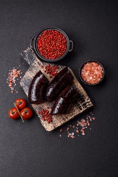Delicious black blood sausage or black pudding with spices and herbs grilled on a black concrete background