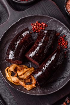 Delicious black blood sausage or black pudding with spices and herbs grilled on a black concrete background