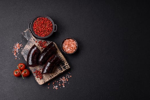 Delicious black blood sausage or black pudding with spices and herbs grilled on a black concrete background