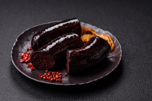 Delicious black blood sausage or black pudding with spices and herbs grilled on a black concrete background