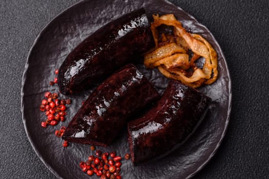 Delicious black blood sausage or black pudding with spices and herbs grilled on a black concrete background