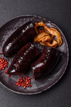 Delicious black blood sausage or black pudding with spices and herbs grilled on a black concrete background
