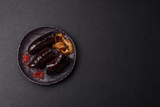 Delicious black blood sausage or black pudding with spices and herbs grilled on a black concrete background