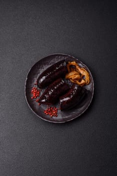 Delicious black blood sausage or black pudding with spices and herbs grilled on a black concrete background
