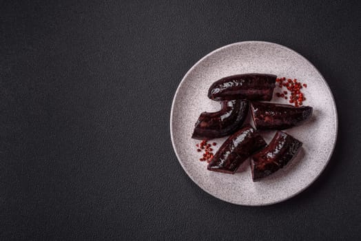Delicious black blood sausage or black pudding with spices and herbs grilled on a black concrete background