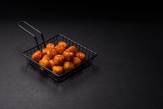 Delicious fried potato balls or croquettes with salt, spices and herbs on a dark concrete background