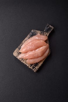 Raw chicken fillet cut into strips with spices and herbs on a wooden cutting board