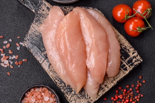 Raw chicken fillet cut into strips with spices and herbs on a wooden cutting board