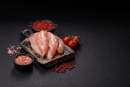 Raw chicken fillet cut into strips with spices and herbs on a wooden cutting board