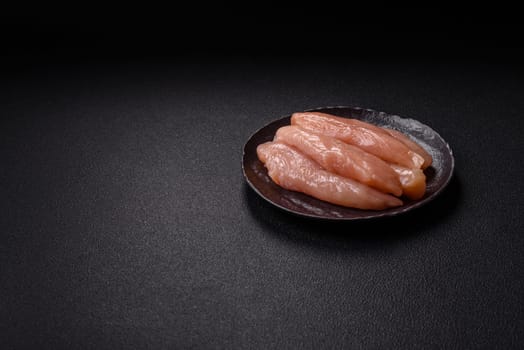 Raw chicken fillet cut into strips with spices and herbs on a wooden cutting board