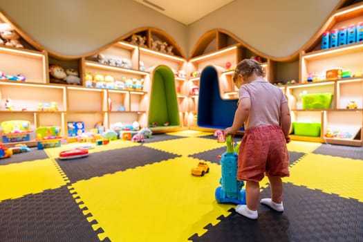 Child exploring a bright and organized indoor playroom with toys and activity stations