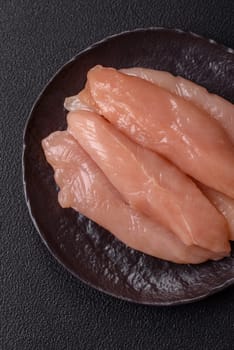 Raw chicken fillet cut into strips with spices and herbs on a wooden cutting board