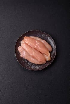 Raw chicken fillet cut into strips with spices and herbs on a wooden cutting board
