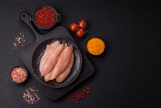 Raw chicken fillet cut into strips with spices and herbs on a wooden cutting board