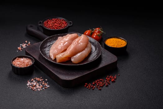 Raw chicken fillet cut into strips with spices and herbs on a wooden cutting board