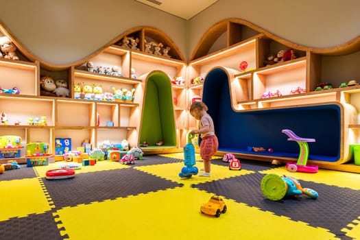 Young child engaged with colorful toys and games in a playful indoor space for fun and learning