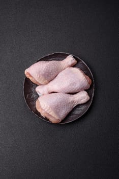 Raw chicken legs with salt, spices and herbs prepared for grilling