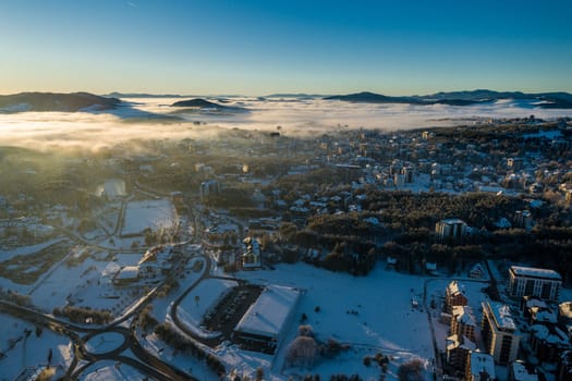 Panoramic aerial view of Zlatibor town and low cloud over Zlatibor Mountain at winter sunset, Cajetina, Serbia.