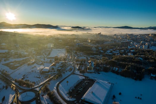 Panoramic aerial view of Zlatibor town and low cloud over Zlatibor Mountain at winter sunset, Cajetina, Serbia.