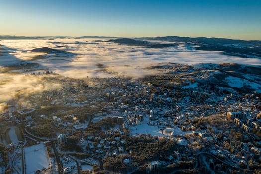 Panoramic aerial view of Zlatibor town and low cloud over Zlatibor Mountain at winter sunset, Cajetina, Serbia.