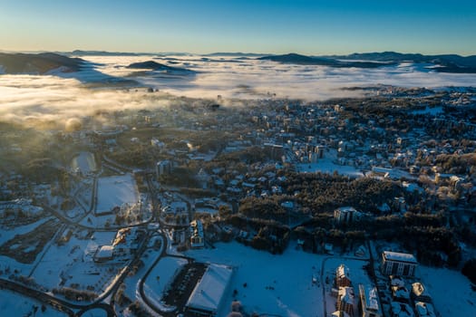 Panoramic aerial view of Zlatibor town and low cloud over Zlatibor Mountain at winter sunset, Cajetina, Serbia.