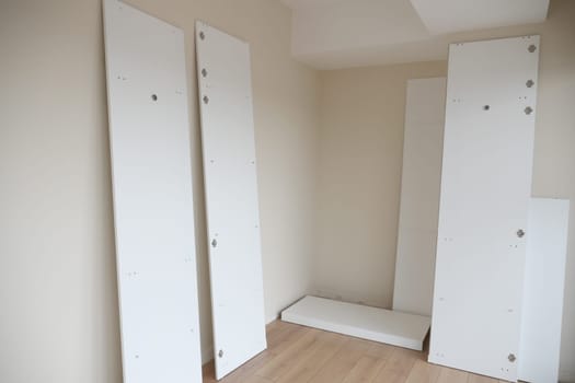 This room is showcasing white furniture panels that are currently waiting to be assembled