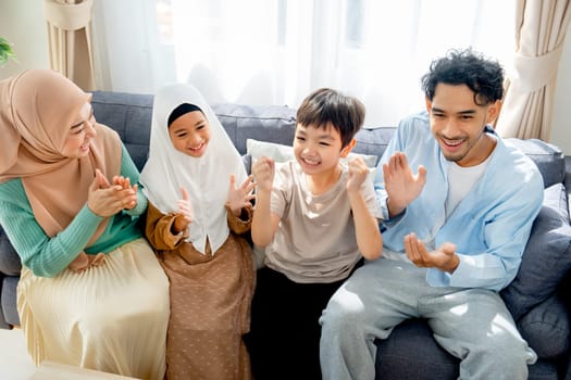 Asian muslim family compose of mother, father, daughter and son express happy for some success of the activity in their house.