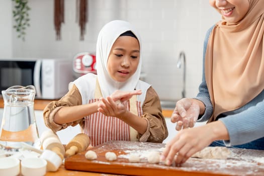 Asian muslim girl enjoy to threshing flour to be like ball shape for making bakery with mother in kitchen of their house.