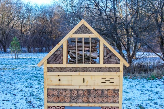 A colorful insect hotel in a snowy park provides winter shelter for beneficial insects, boosting local biodiversity and conservation.