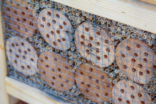 A decorative insect hotel showcases a variety of wooden logs and hollow tubes, providing shelter for beneficial insects in the garden.