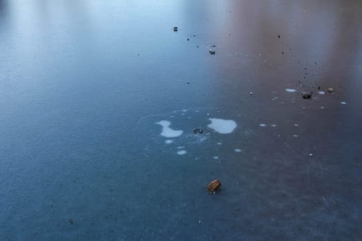 A frozen surface reflects light as scattered debris creates abstract shapes in a calm atmosphere.