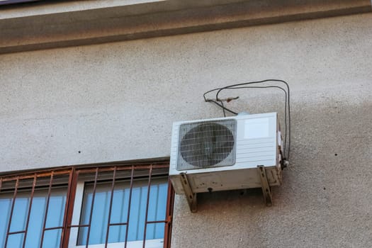 An exterior air conditioning unit is mounted on a building wall, providing cooling during the hot summer months. The sun casts a warm glow.
