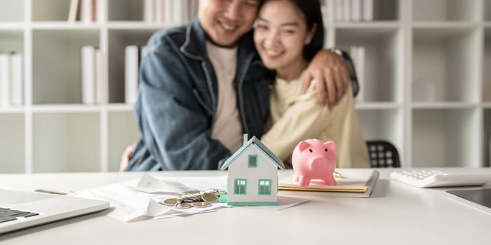 Happy asian family young couple love hand . piggy bank to save and model home for saving money to buy for new home. deposit with bank for financial plan.