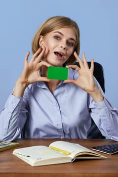 cheerful blonde business lady holding plastic credit card on blue background