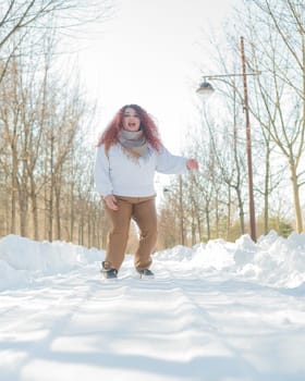 Smiling plump redhead woman jumping in park in winter