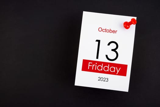 Calendar Friday the 13th October 2023 and push pin on black color background.