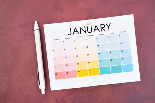 January 2024 calendar page and pen on red color retro background.
