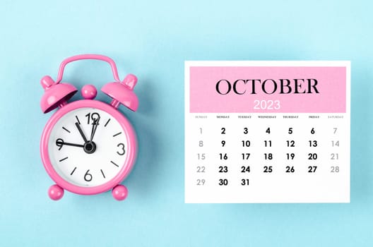 October 2023 Monthly calendar for 2023 year with pink color alarm clock on blue background.
