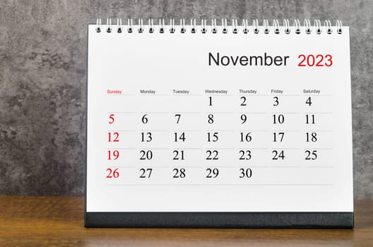 November 2023 Monthly desk calendar for 2023 year on wooden table.