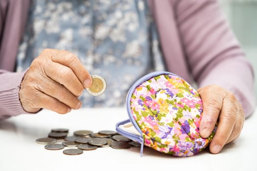 Asian senior woman holding counting coin money in purse. Poverty, saving problem in retirement.