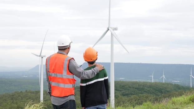 Engineer with his son on a wind farm atop a hill or mountain in the rural. Progressive ideal for the future production of renewable, sustainable energy. Energy generation from wind turbine.